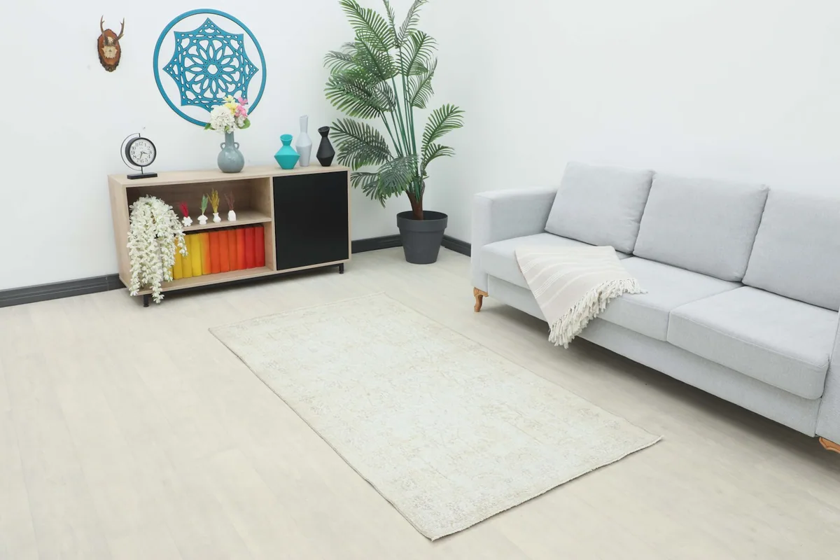 Ivory vintage area rug placed in a modern living room setting with a gray couch and light flooring