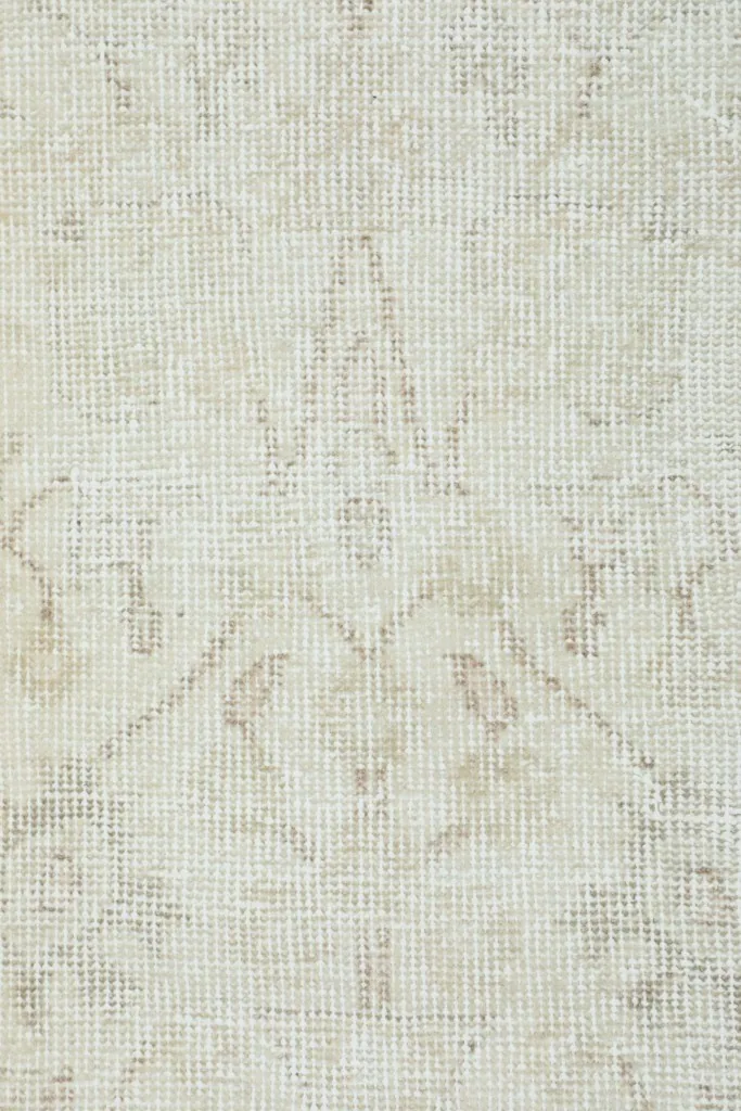Very close detail of the rug's low wool pile and the hand-knotted texture with faded tan elements