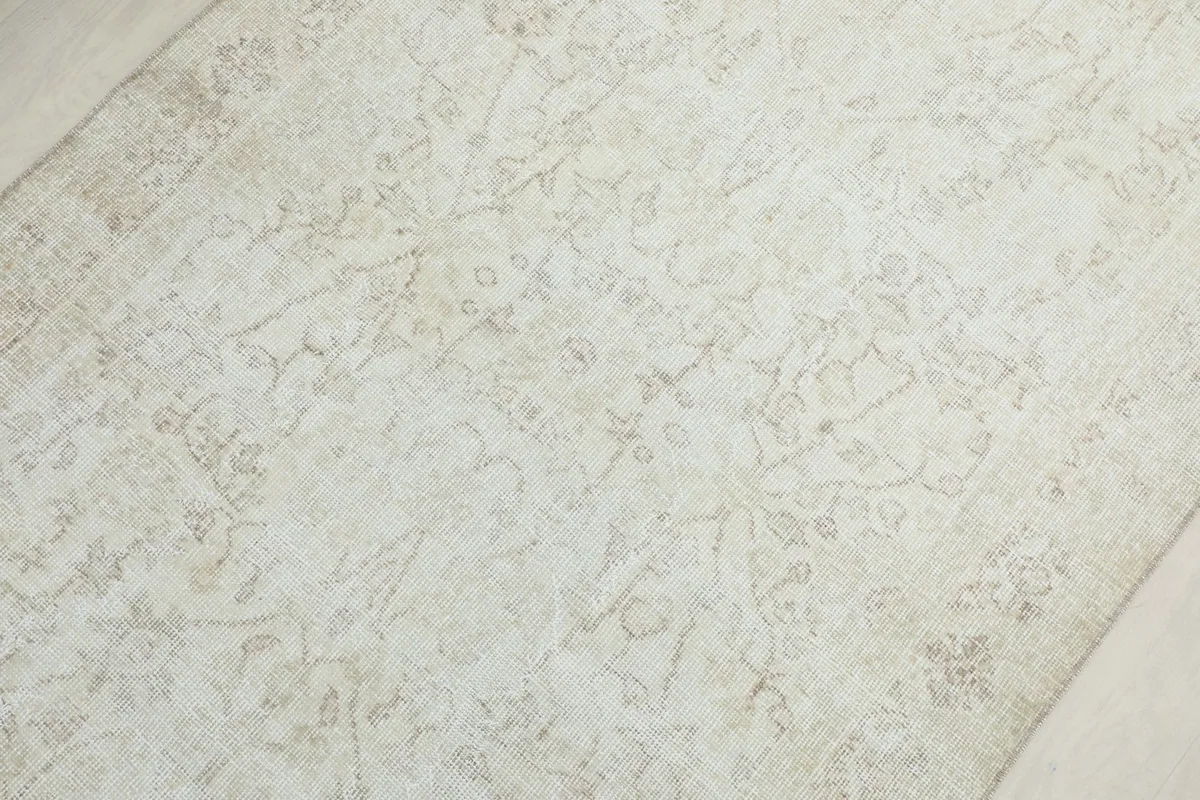 Overhead close-up showing the central floral and medallion motifs across the ivory rug's field