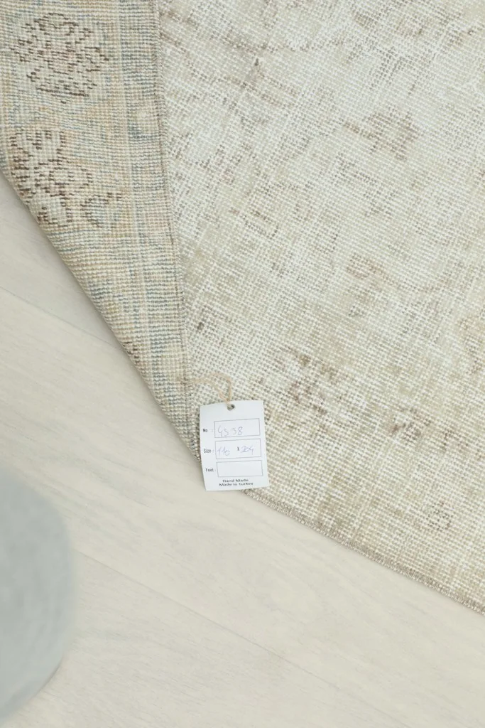 Close-up of the rug's back, displaying the care label and the tight knotting of the vintage piece