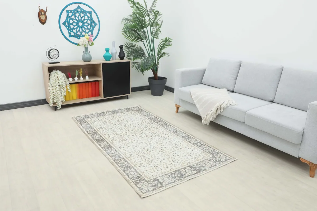 Ivory and gray vintage Anatolian rug placed in a modern living room setting with a light gray sofa.