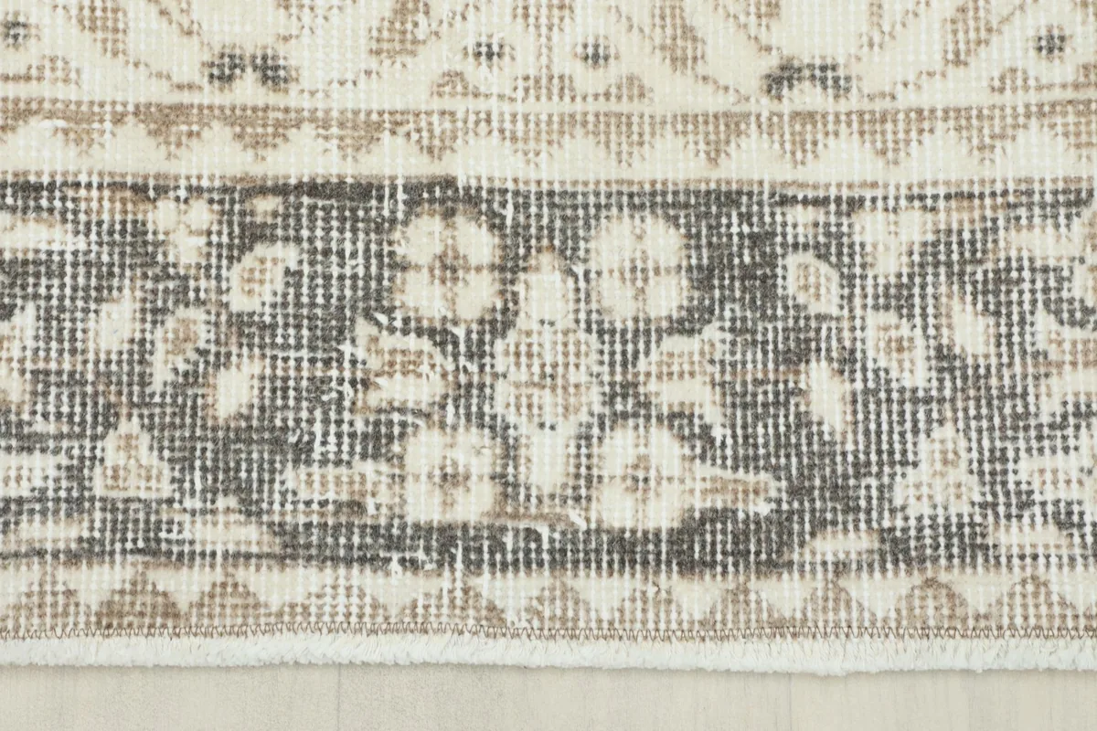 Detailed view of the rug's gray border, showcasing its traditional floral and geometric patterns.