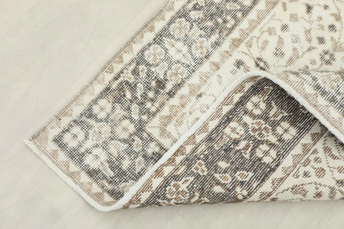 Corner of the rug folded back, revealing the reverse side and the hand-knotted wool on cotton foundation.