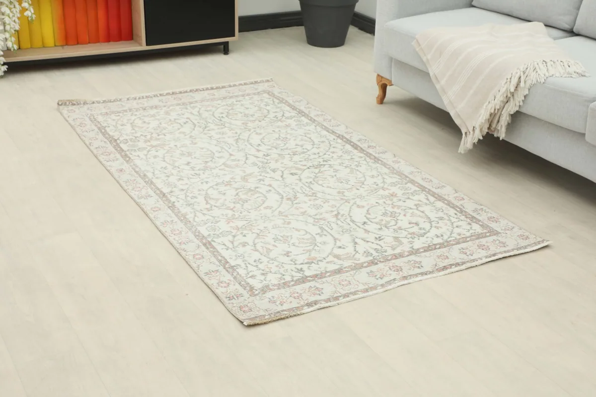 Angle view of the ivory floral rug in a room, showing its placement next to a sofa