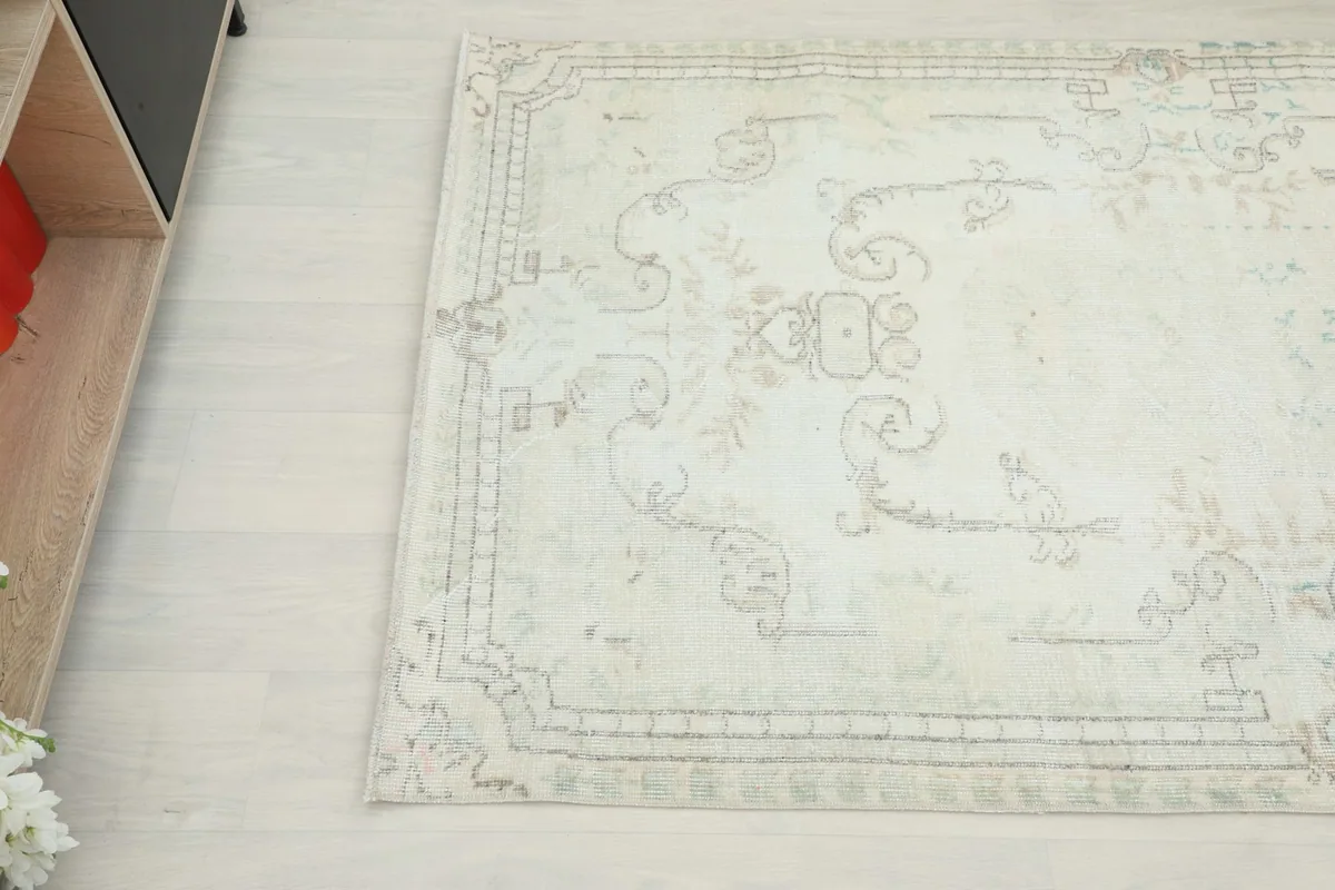 Angled view of the rug's edge and part of the design next to a piece of furniture