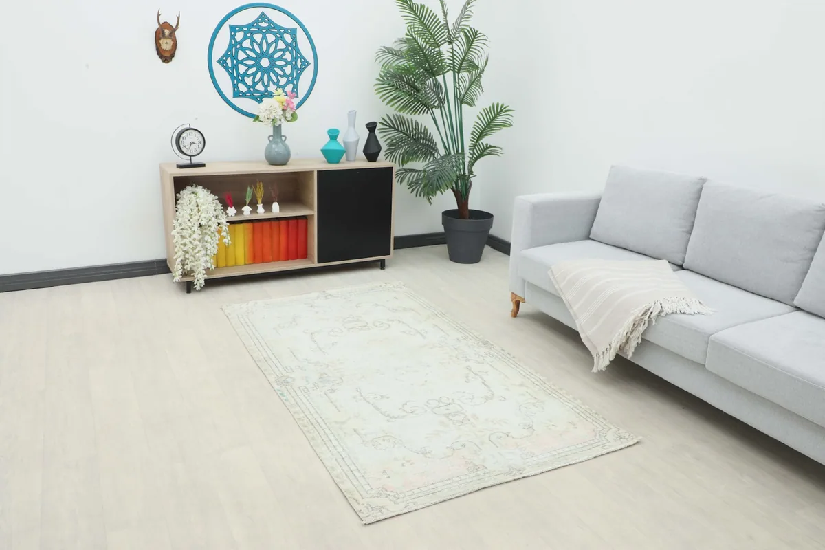 Vintage ivory rug in a modern living room setting next to a sofa and cabinet