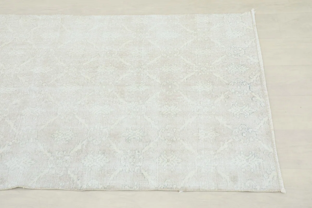 Corner view of the ivory rug showing its low pile and muted design