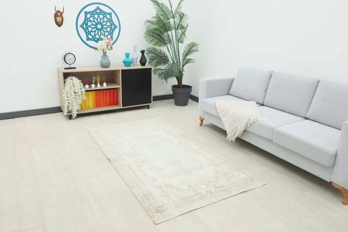 Beige vintage rug placed in a living room setting with a sofa and cabinet