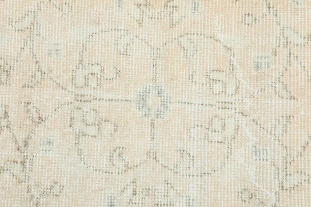 Macro detail of the hand-knotted wool pile showing the faded floral design