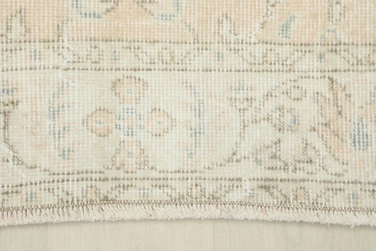 Close-up of the rug's border design and fringe, highlighting the muted colors