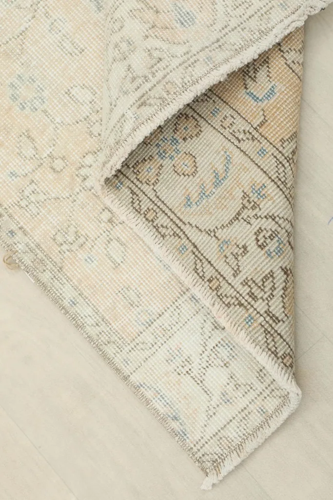 Corner of the rug folded to reveal the cotton foundation and reverse side