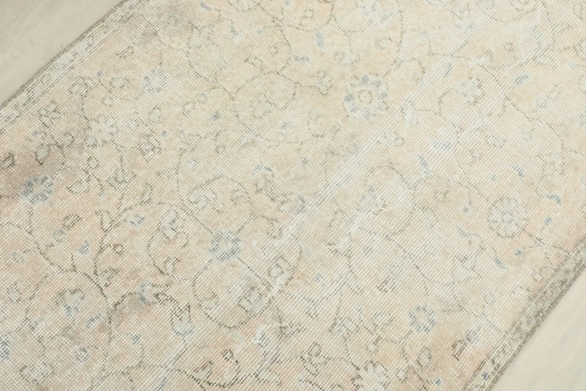 Overhead close-up of the central field of the rug with its muted ivory and blue patterns