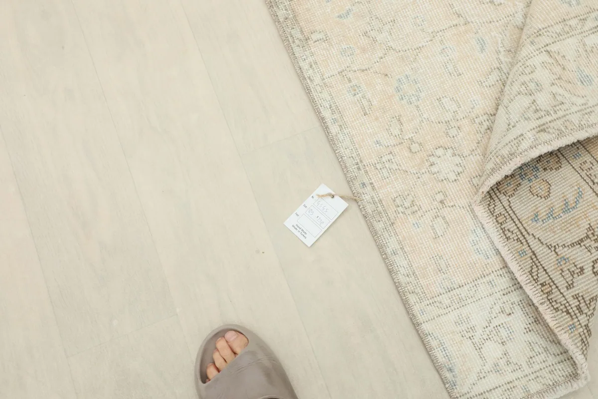 Overhead view of a foot next to the folded rug, indicating scale
