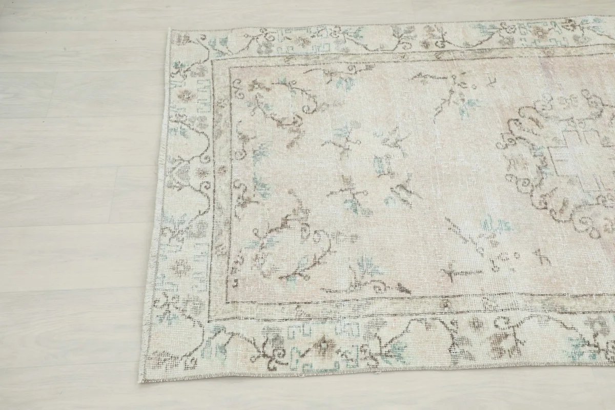 Close-up angled view of the rug's pattern and border, revealing subtle color variations and wear.