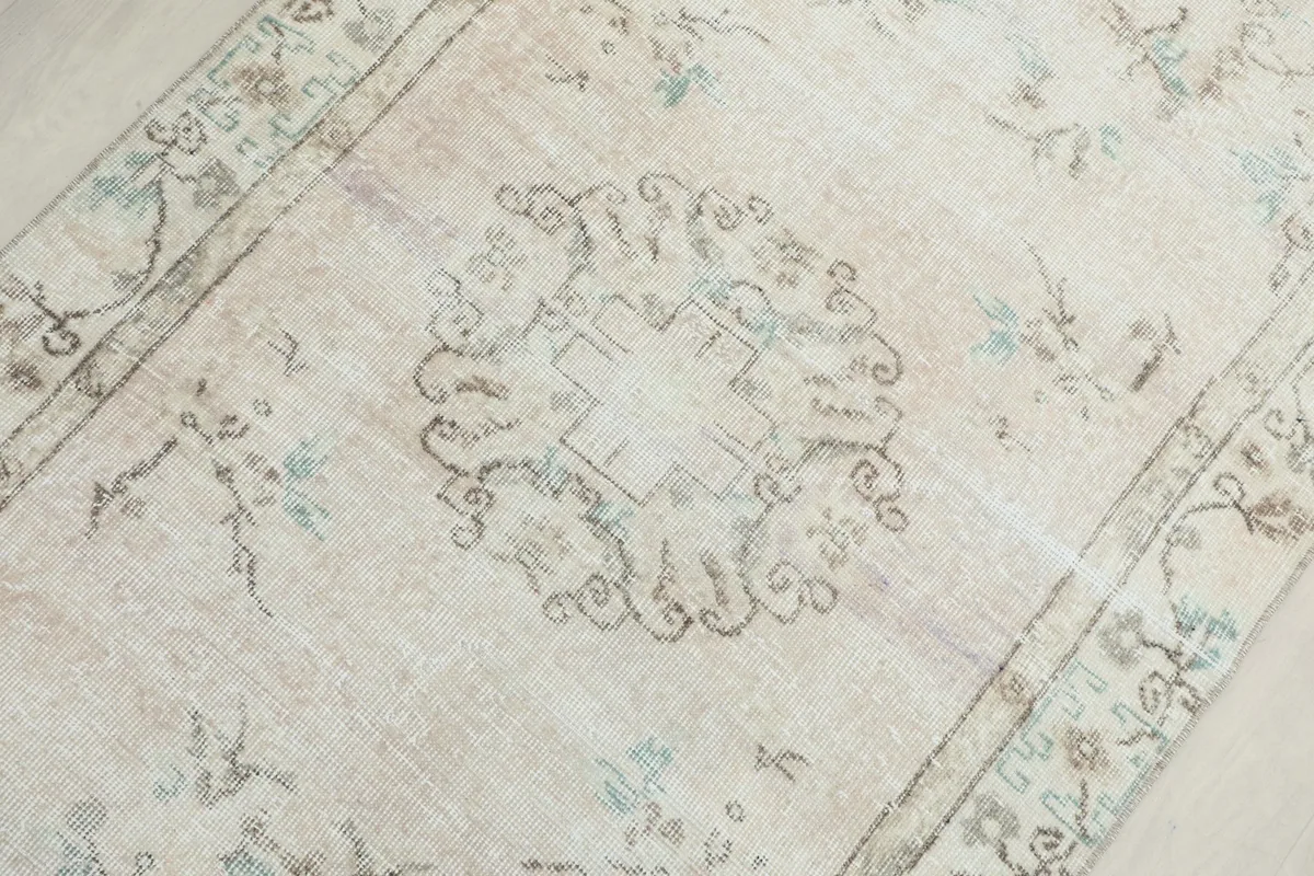 Detailed view of the central medallion and surrounding faded floral motifs on the ivory field.