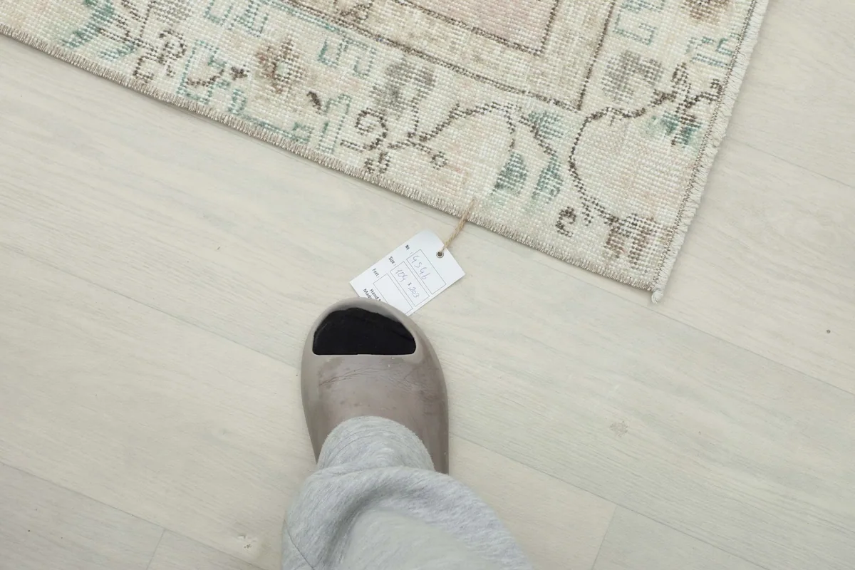Foot next to the rug to provide a sense of scale and texture of the vintage wool pile.