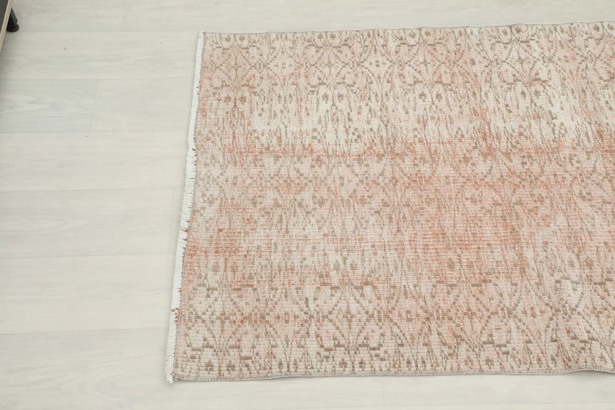 Close-up angled view of the other end of the rose vintage rug, showing the subtle color variations.