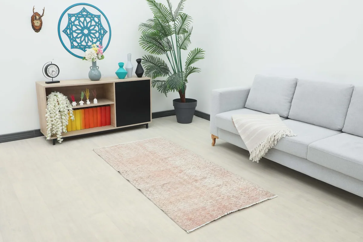 Rose geometric vintage rug styled in a living room next to a light gray couch and wooden console.