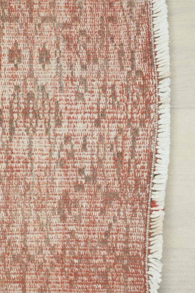 Close-up of the short, subtle fringes and the end of the rose geometric vintage rug.