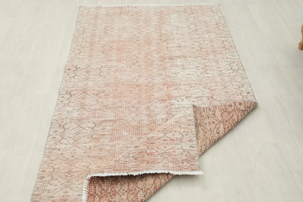Rug with a corner folded over, displaying the front and back textures of the vintage piece.