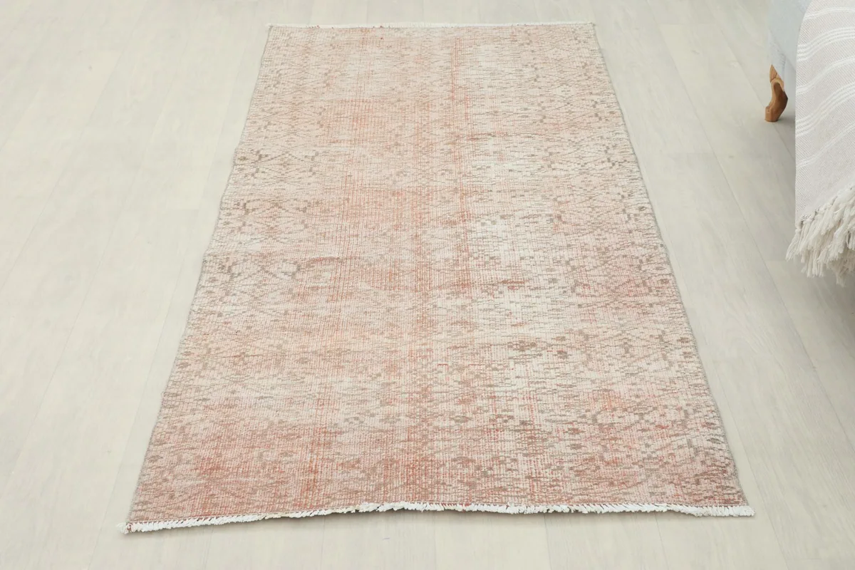 Full overhead view of the rose geometric vintage Anatolian rug laid out on a light wood floor.