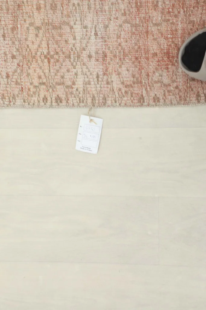 Overhead view showing a small tag on the floor next to the rose geometric vintage rug.