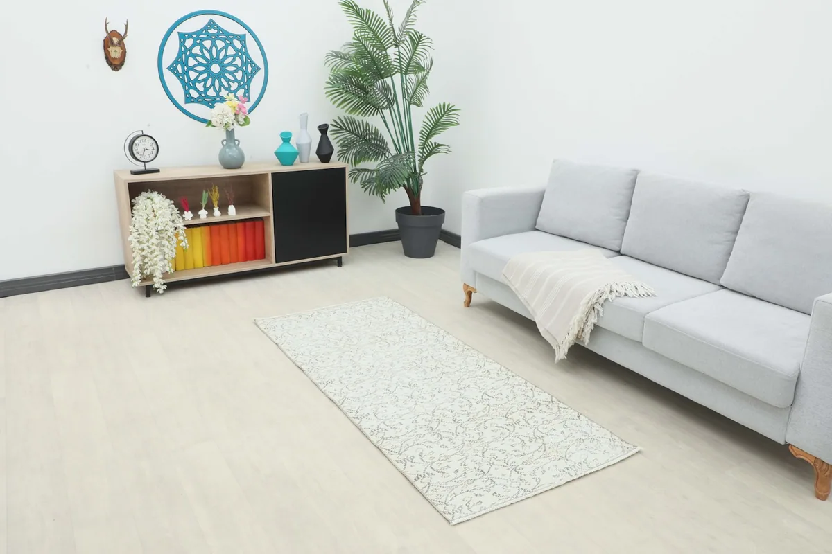 Ivory vintage runner rug displayed in a modern living space with a light gray sofa and wooden furniture.