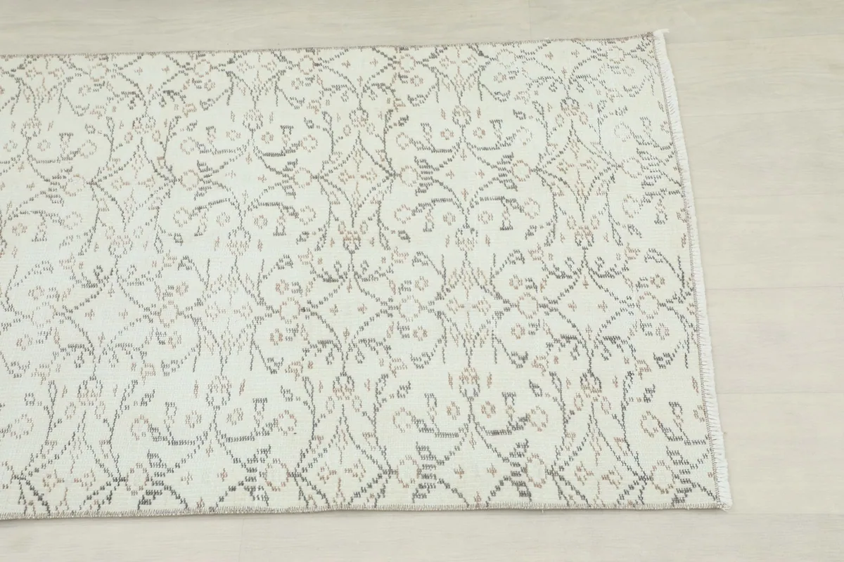Close-up detail of the ivory field and subtle brown and gray floral pattern of the rug.