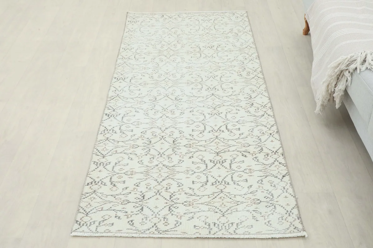 Full overhead shot of the ivory runner rug laid out on a light floor, next to a sofa.