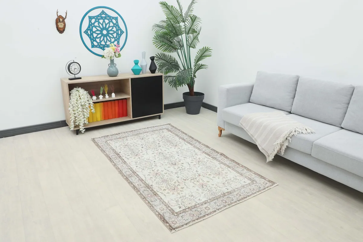 The cream and rose vintage rug placed in a modern living room setting with a gray sofa