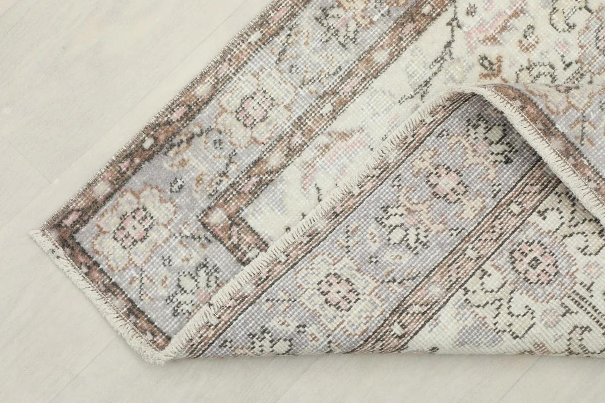 Corner of the vintage rug folded to reveal the cotton foundation and hand-knotted back