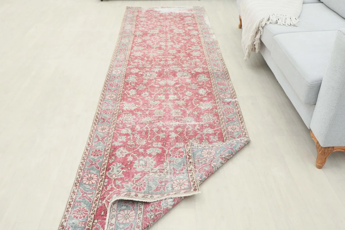 Angled view of the entire runner rug laid out in a room, with a corner slightly lifted.