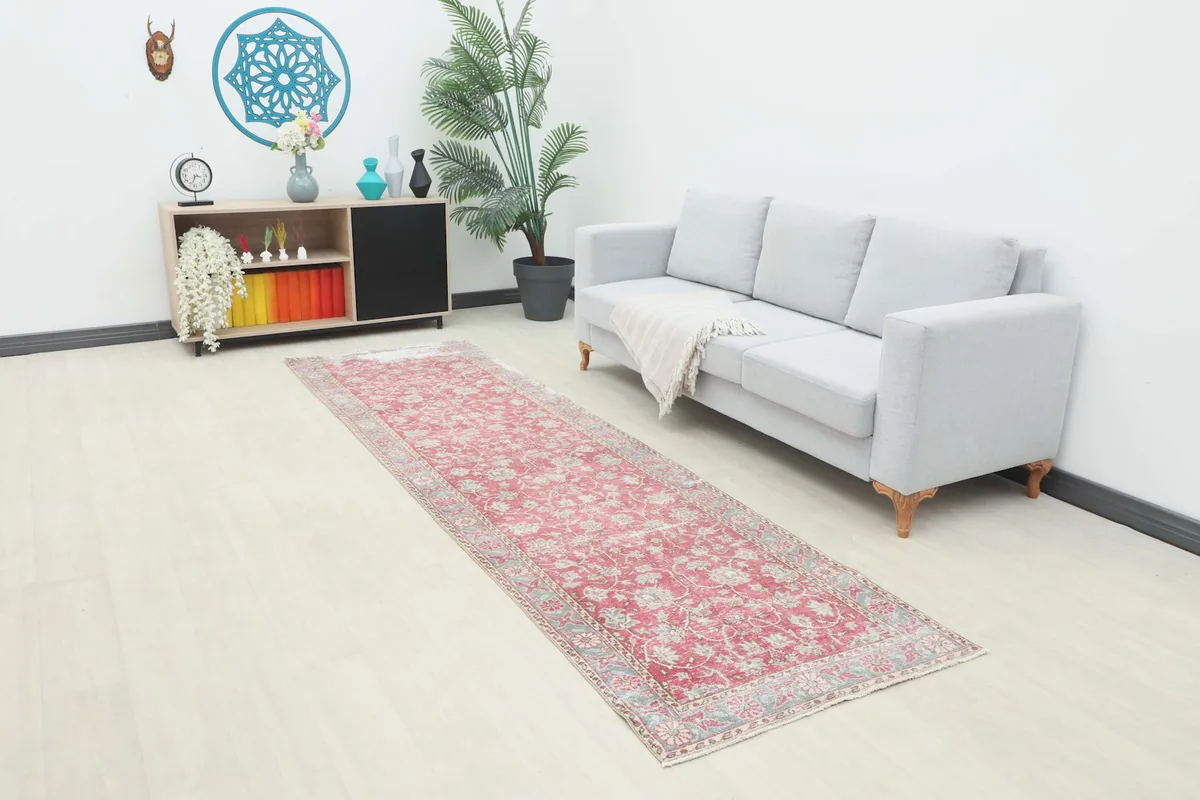 Vintage rose and gray floral runner rug extending in a living room setup with a light gray couch.
