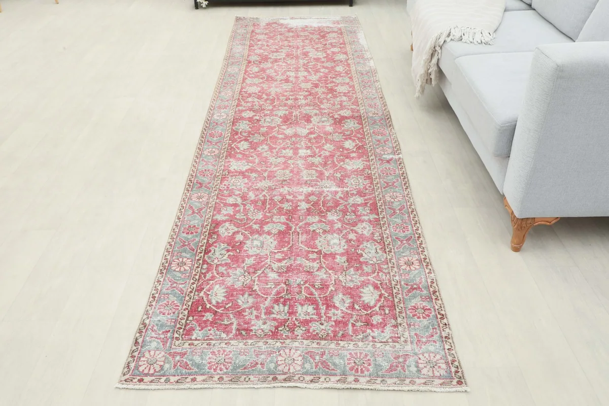 Full view of the vintage rose and gray runner rug placed in a room, offering a sense of its scale.