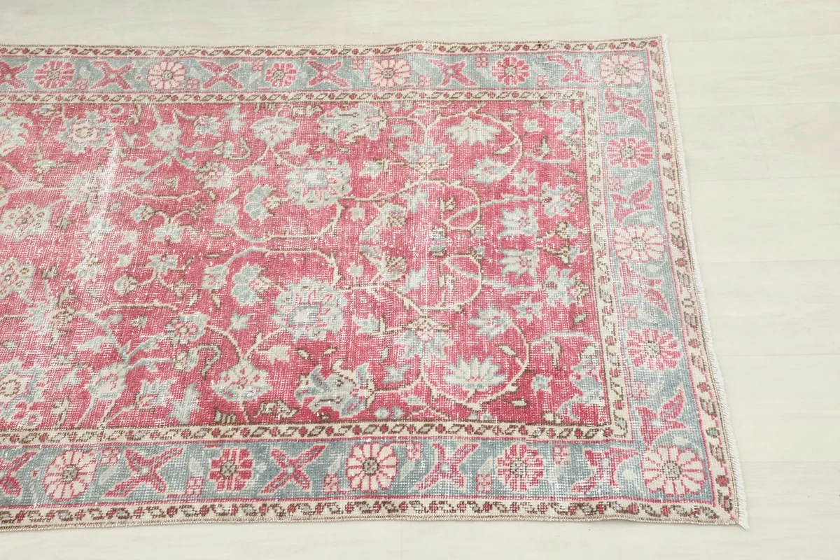 Close-up of the rose field and gray floral border of the Anatolian runner rug, showing the faded colors.