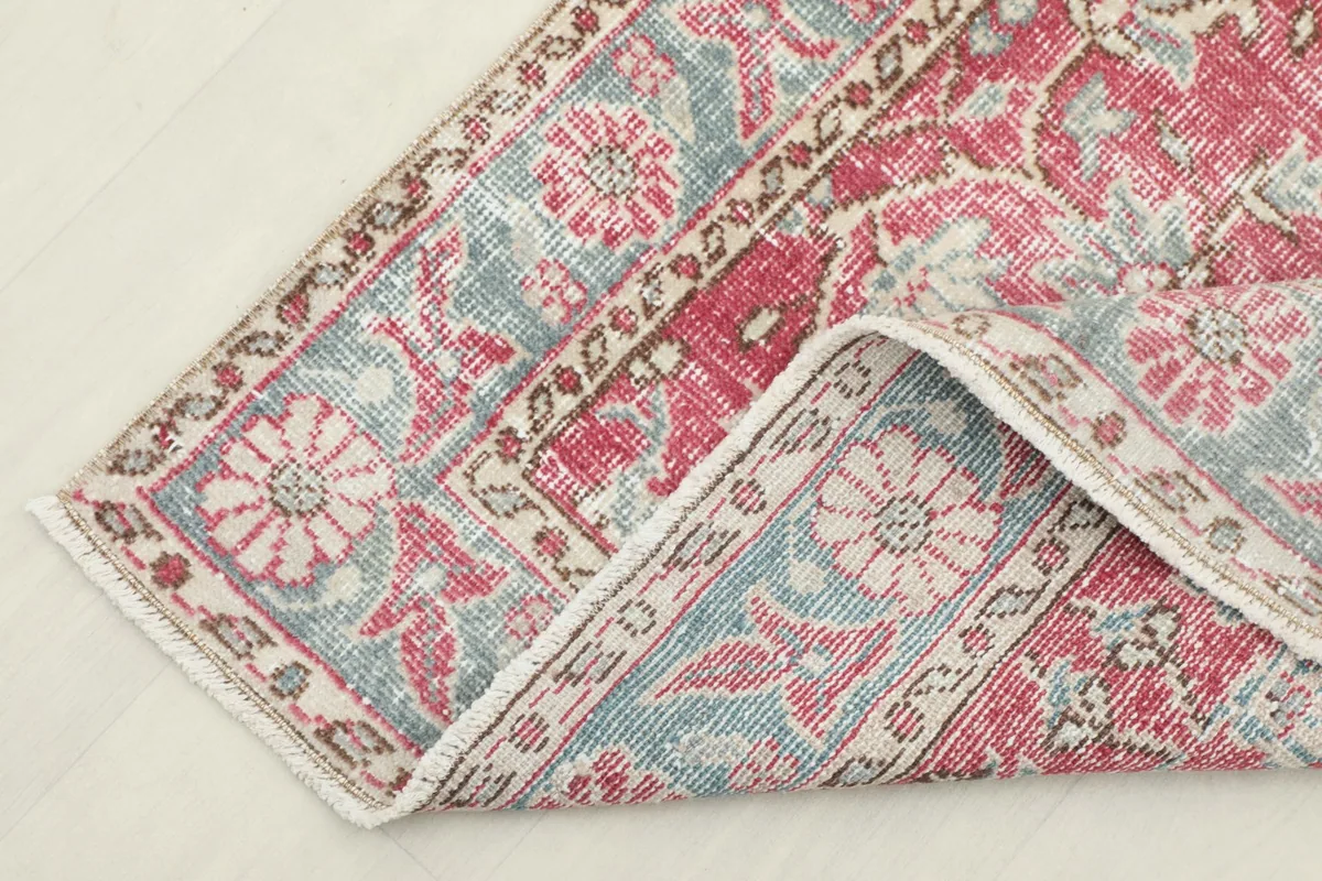 Corner of the runner rug folded back, showing the back of the rug and the border design.