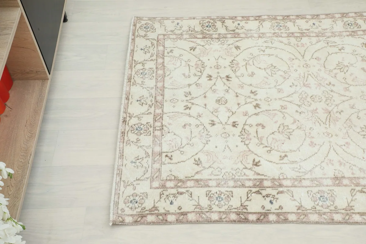 Overhead angle showing the intricate floral pattern and subtle rose hues in the rug