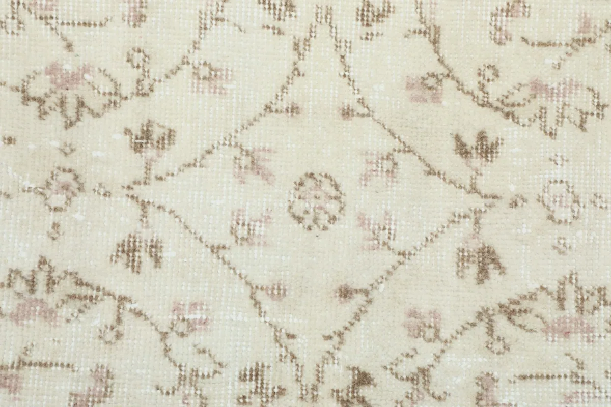 Close-up of the hand-knotted texture and faded tan and rose colors in the wool pile
