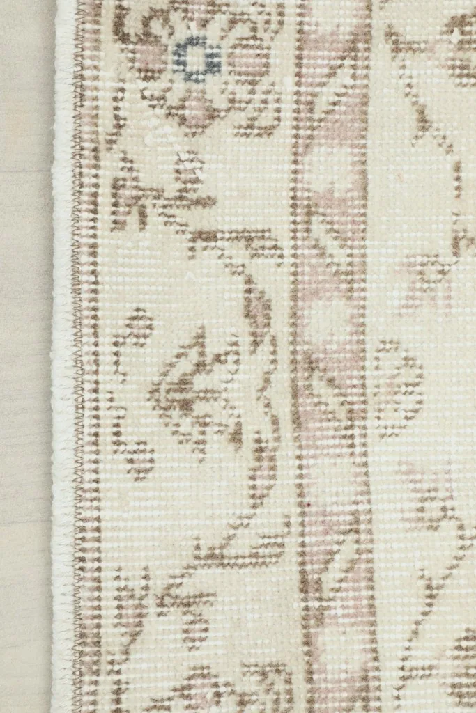 Detailed view of the rug's outer border with a traditional floral design and fringe