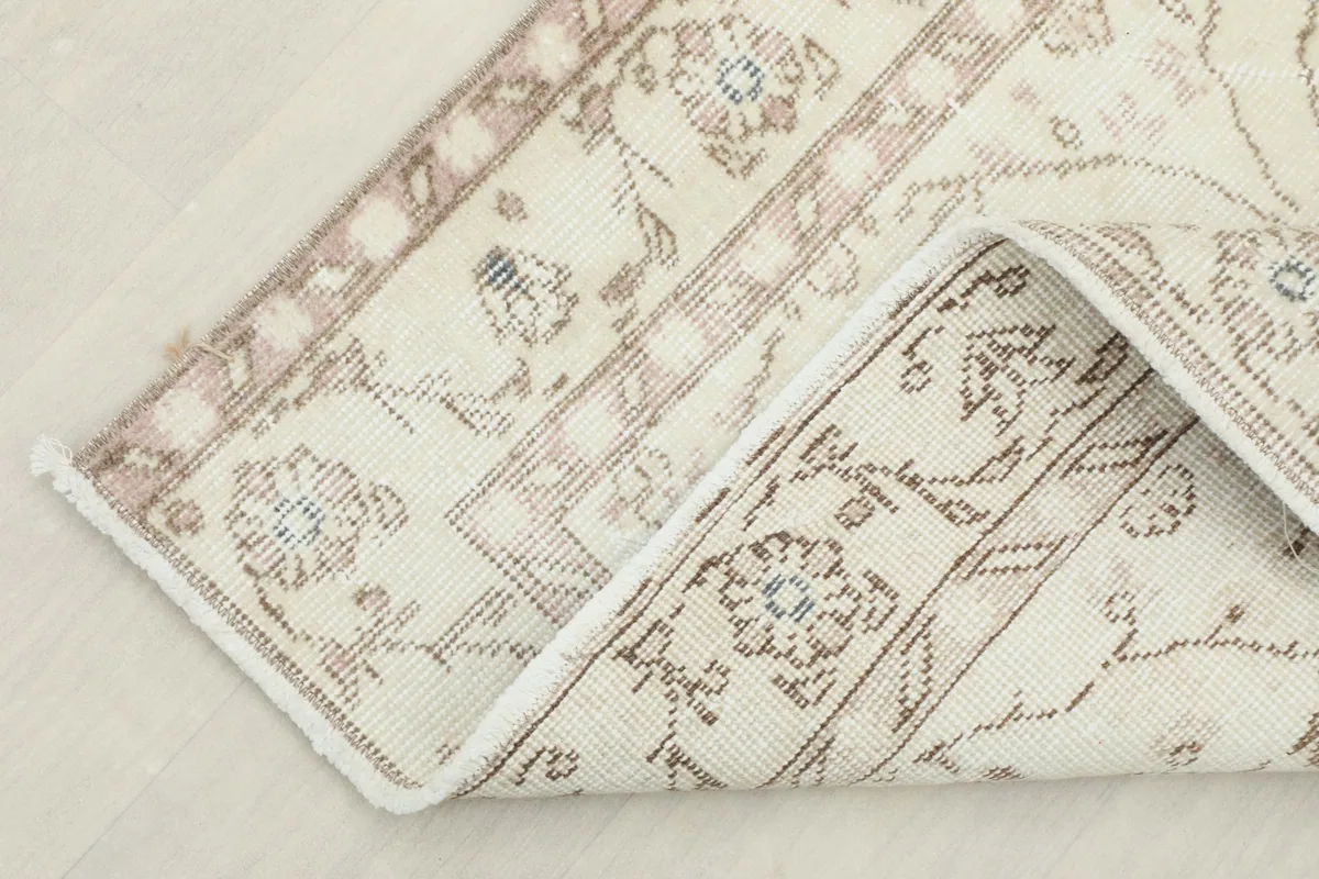 Corner of the rug folded back, revealing the cotton foundation and hand-knotted construction
