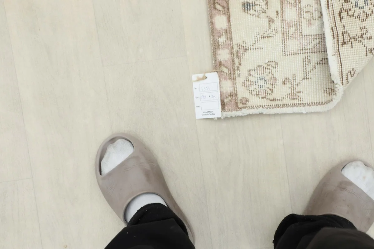 Feet in slippers next to the folded rug, providing a sense of scale and texture