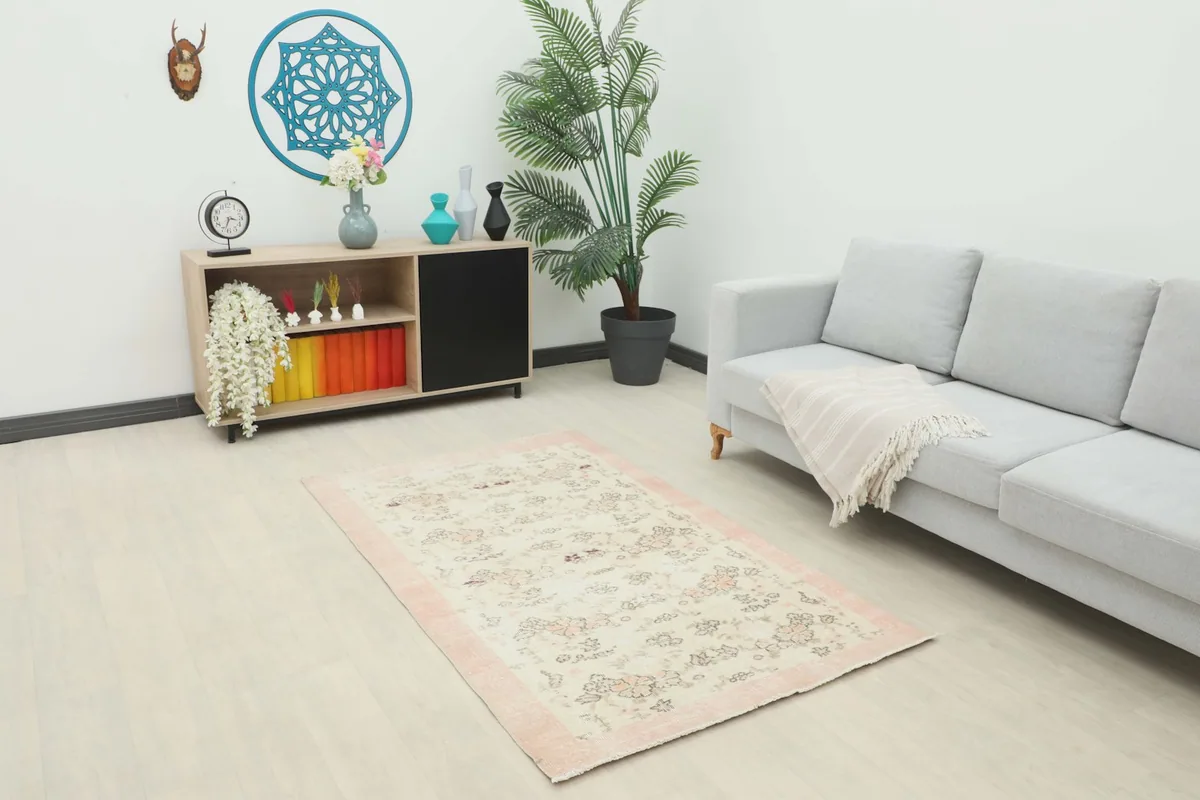 Vintage Anatolian rug displayed in a bright living room setup with a sofa and cabinet