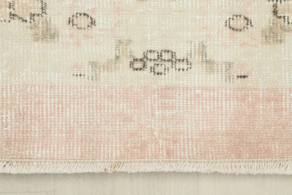 Close-up of the rug's pink border and short fringe, revealing the hand-knotted texture