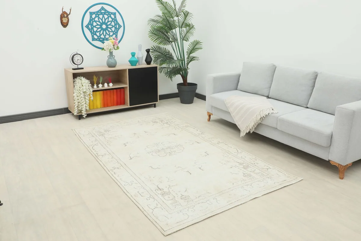 Ivory vintage Anatolian rug placed in a living room setting with a light gray sofa.