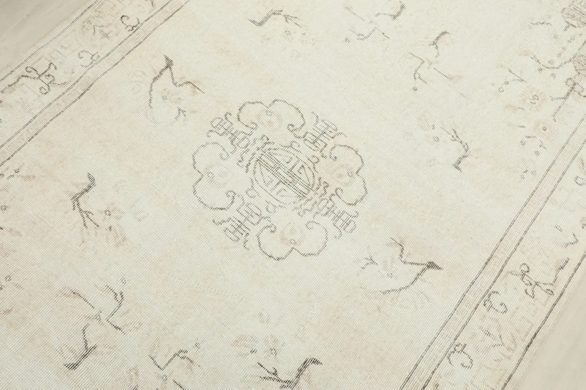 Detailed view of the central gray medallion and surrounding geometric motifs on the ivory rug.
