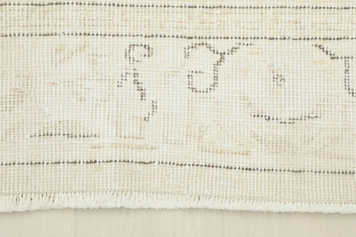 Close-up of the rug's border design, showing the subtle gray patterns and natural fringe.