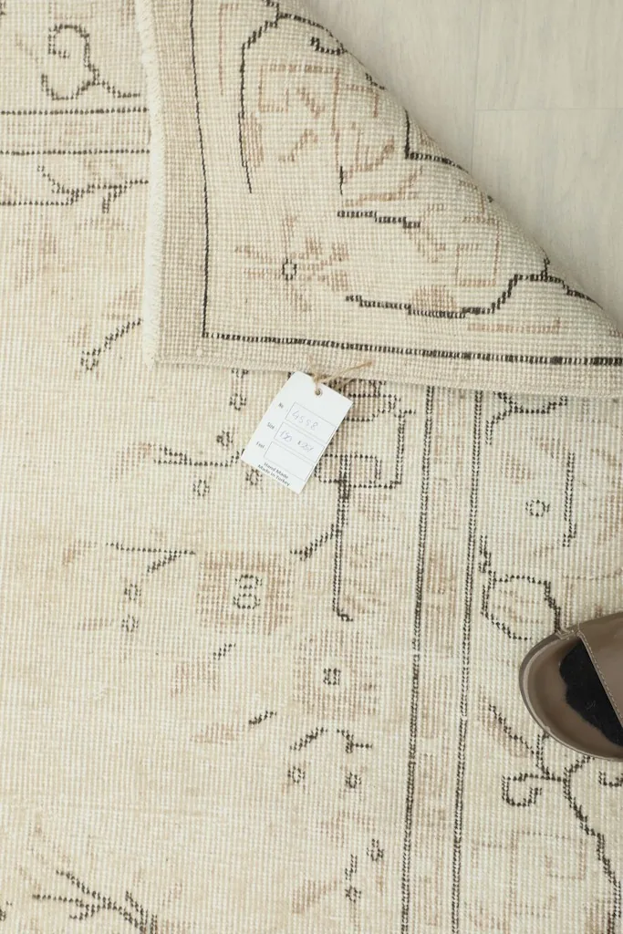 Overhead view of the rug's reverse side, displaying the tag and intricate knotting of the cotton foundation.