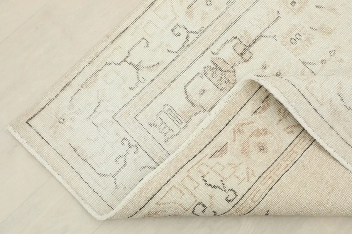 Folded corner of the rug revealing the cotton foundation and the reverse side's weave.