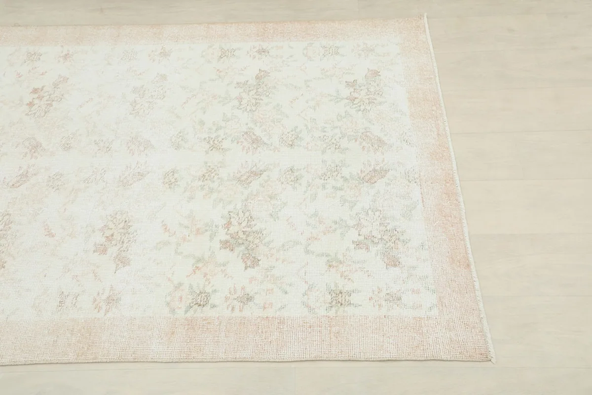 Close-up of the corner of the cream rug, showing floral patterns and beige border