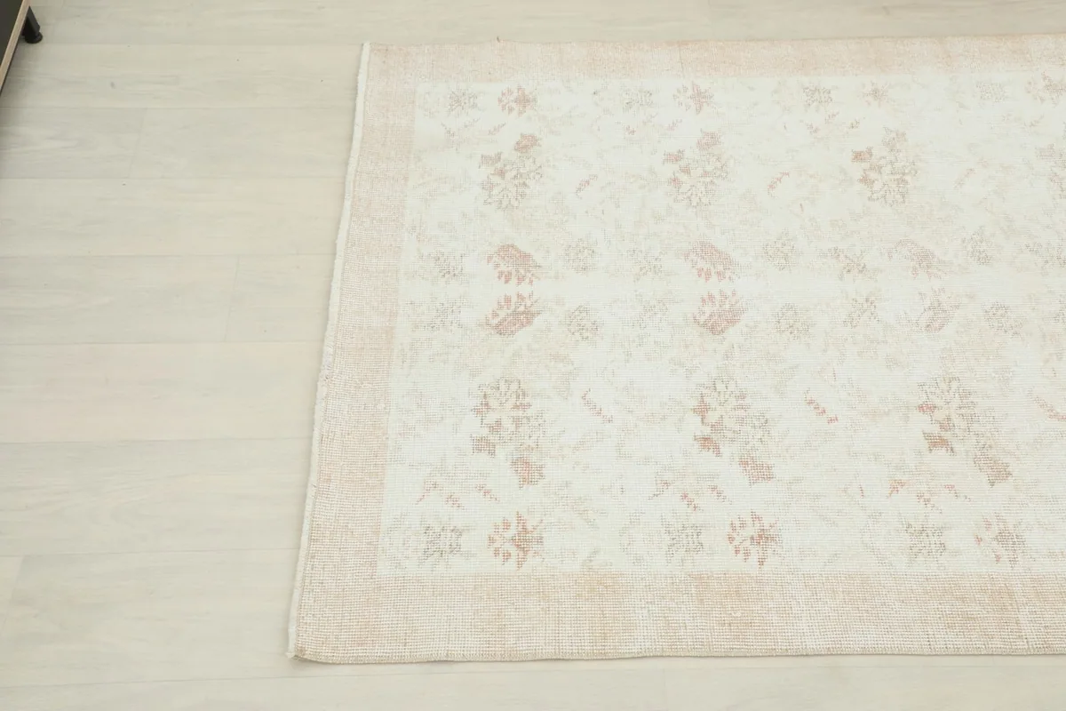 Detailed view of the opposite corner of the cream rug, highlighting the subtle floral design